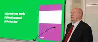 A man in a suit and red tie stands at a podium labeled "fieldfisher." He is giving a presentation in front of a screen displaying the slide title "SCOPE" with three bullet points: (1) In their own words (2) What happened (3) Action now.