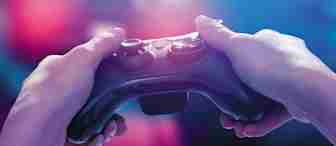 Close-up of a person holding a black gaming controller with both hands. The background is blurred with neon blue and pink lighting, creating a vibrant and immersive atmosphere.