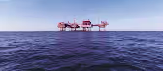 An offshore oil platform stands in the middle of the ocean against a backdrop of a clear, blue sky. The structure is supported by multiple stilts and has various cranes and equipment on top. The calm sea below reflects the purple hues of the platform.