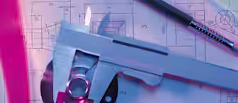 A close-up of engineering tools placed on technical blueprints. Visible are a vernier caliper, a pen, a precision screwdriver, a metal part, and drawing templates, all under blue and pink lighting. The blueprints display detailed mechanical diagrams and measurements.