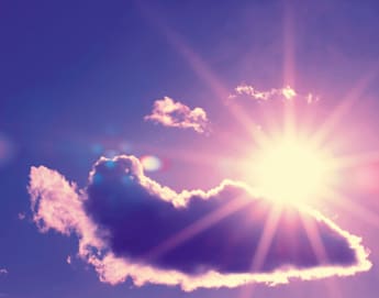 A brilliant sun shines behind a fluffy cloud in a purple and blue sky. Sun rays radiate outward, casting a warm glow around the cloud. A hint of lens flare adds an ethereal touch to the vibrant scene.