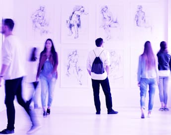 People are walking and observing artwork in a brightly lit gallery. Sketches of human figures are displayed on the wall, and a sculptural piece is seen on the right. The scene has a purple hue. Six individuals are visible, some in motion and others standing still.