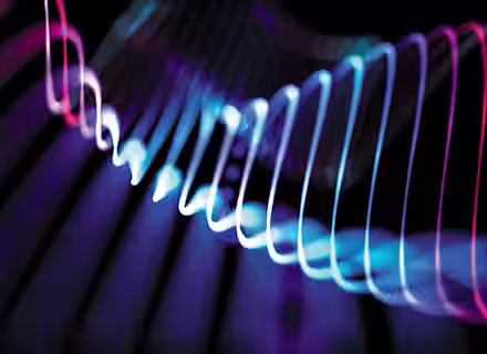 A vibrant, abstract image featuring intertwined neon lights in blue, pink, and purple hues against a dark background. The lights form fluid, wavy shapes that create a dynamic and visually stimulating pattern.