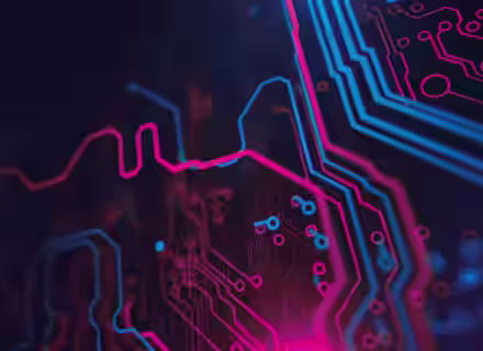 A close-up image of a circuit board illuminated with neon pink and blue lights against a dark background. The intricate pathways and components create a modern, high-tech visual.