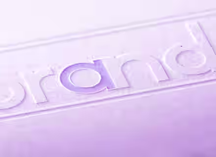 A close-up image shows the word "brand" embossed on a textured surface. The "a" in the word is highlighted in a light purple color. The entire image has a purple tint.