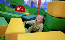 Shows young baby keeping cool in the air conditioned soft play
