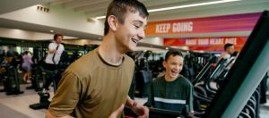A pair of teenagers safely using gym equipment and having fun.