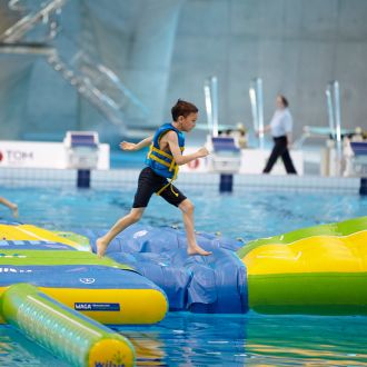 child runs across inflatables in a swimming pool