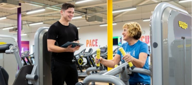 Trainer assist a member on machine in the gym
