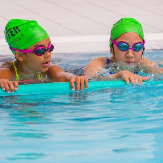 Two children swimming with a float