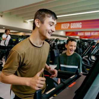 Two junior members laughing while on treadmills