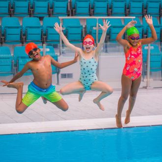Three children happily jumping in the pool
