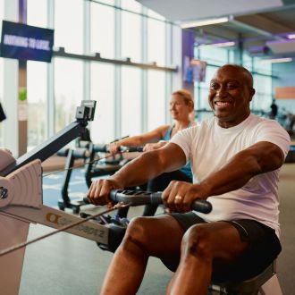 man on rower with female on rower behind in gym