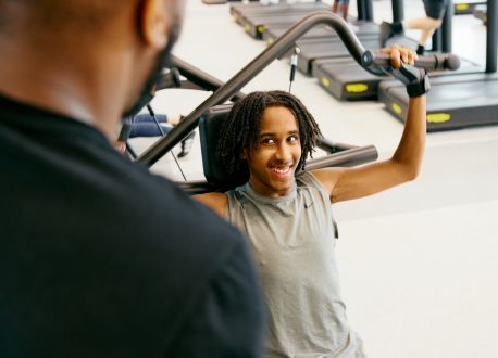 young male being coached on a resistance machine