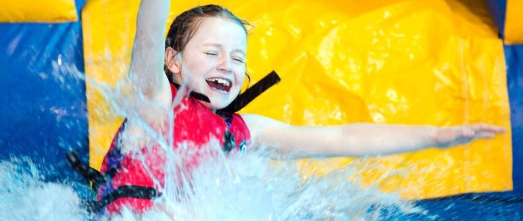 child splashing into the water with brightly coloured large inflatable