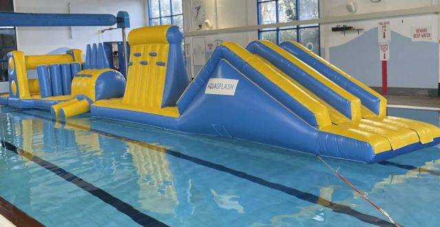 Image shows the blue and yellow aqua splash inflatable laid out in the main pool of Saltash Leisure Centre.