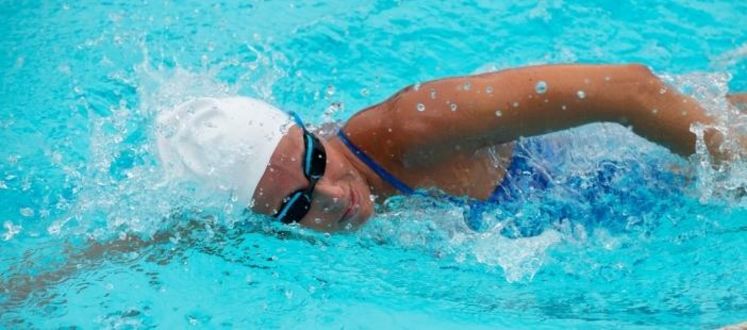 lady wearing swim hat swimming front crawl