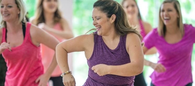 ladies wearing brightly coloured tops dancing in a bright studio space