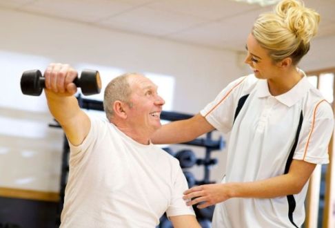 Instructor assisting man with correct technique for using hand weights