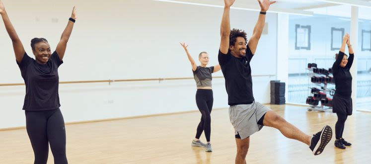 image shows a group of people exercising with their hands in the air