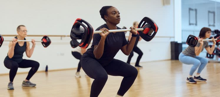 image shows a group of people lifting weights in a fitness class
