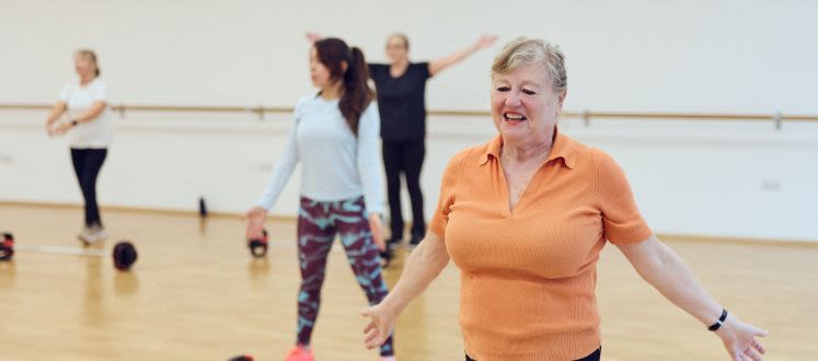 image shows a group of people smiling in a fitness class