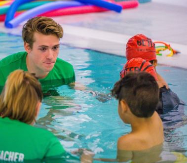 Swimming instructor teaching a group of children in an indoor pool.
