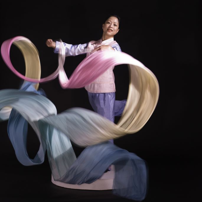 A woman in Chinese dress with ribbons swirling through the air A woman in Chinese dress with ribbons swirling through the air