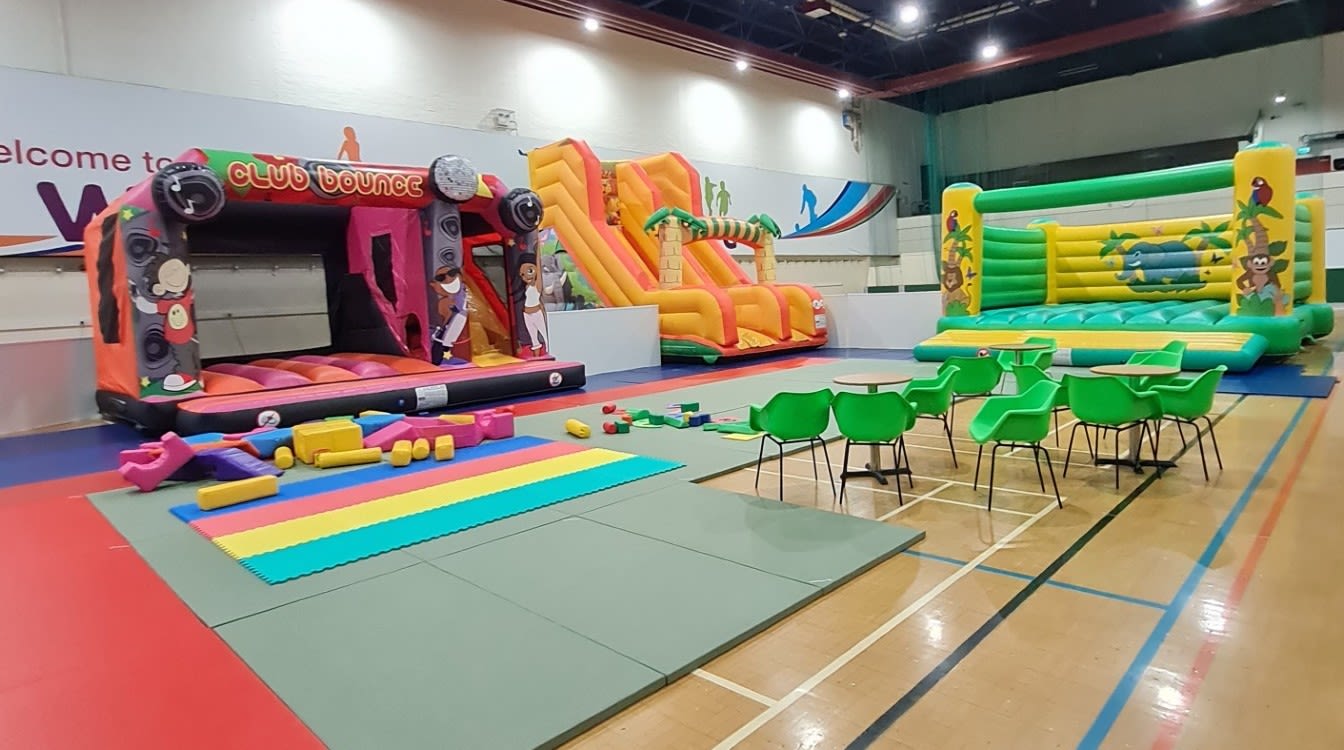 An image of two of the bouncy castles, the large slide, the soft play area, as well as parent/guardian seating.