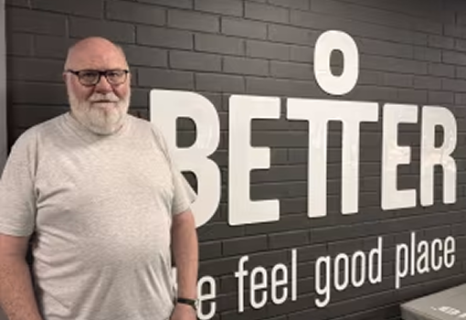 Pete standing in front a sign at the gym Pete standing in front a sign at the gym