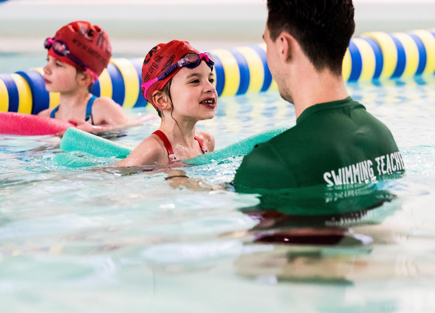 children with swim instructor in a pool