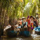 people with conical hats in boats rowing down the mekong delta
