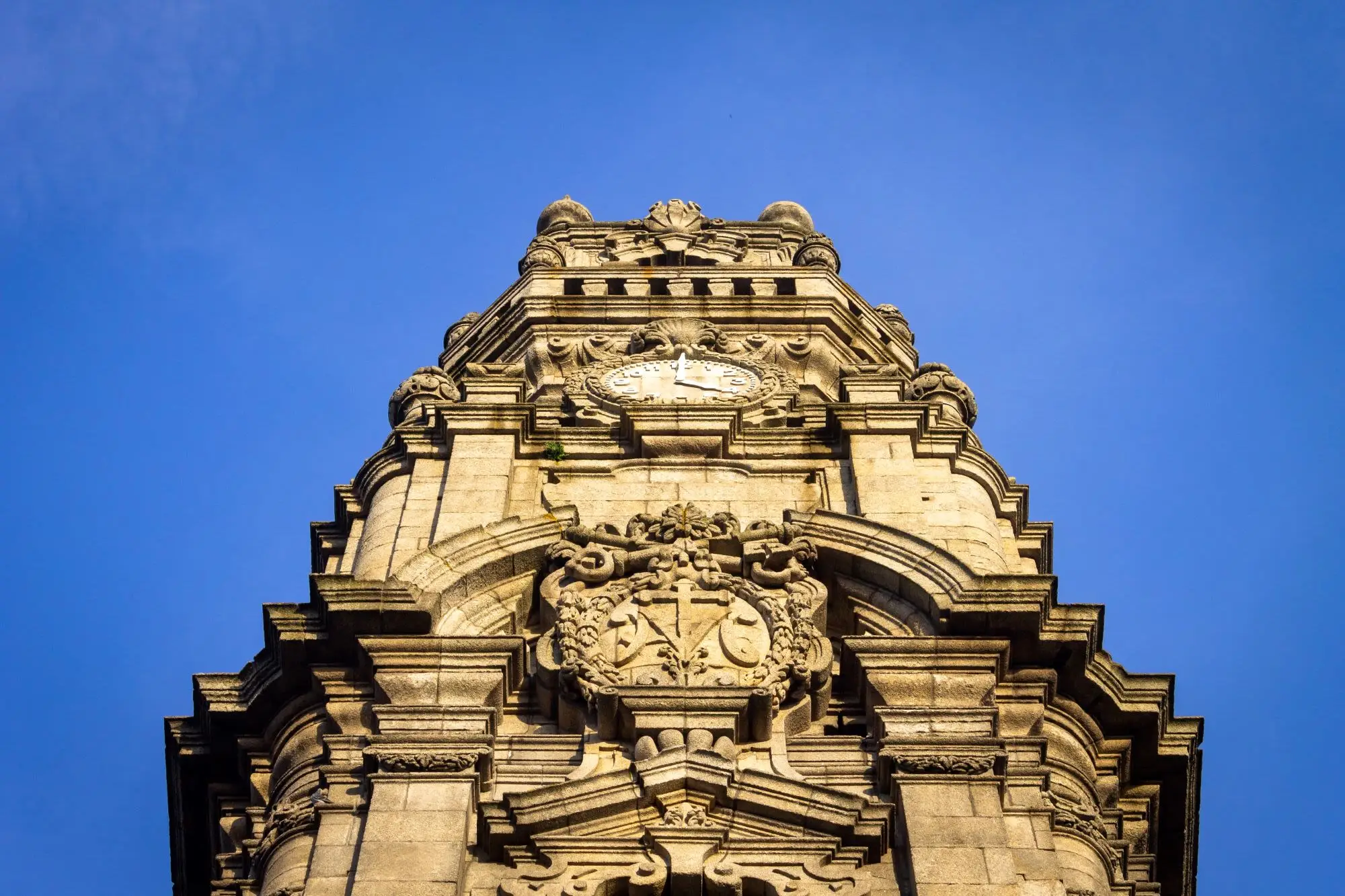 Ground Perspective of the Torre dos Clerigos in Porto, Portugal against a clear blue sky background.