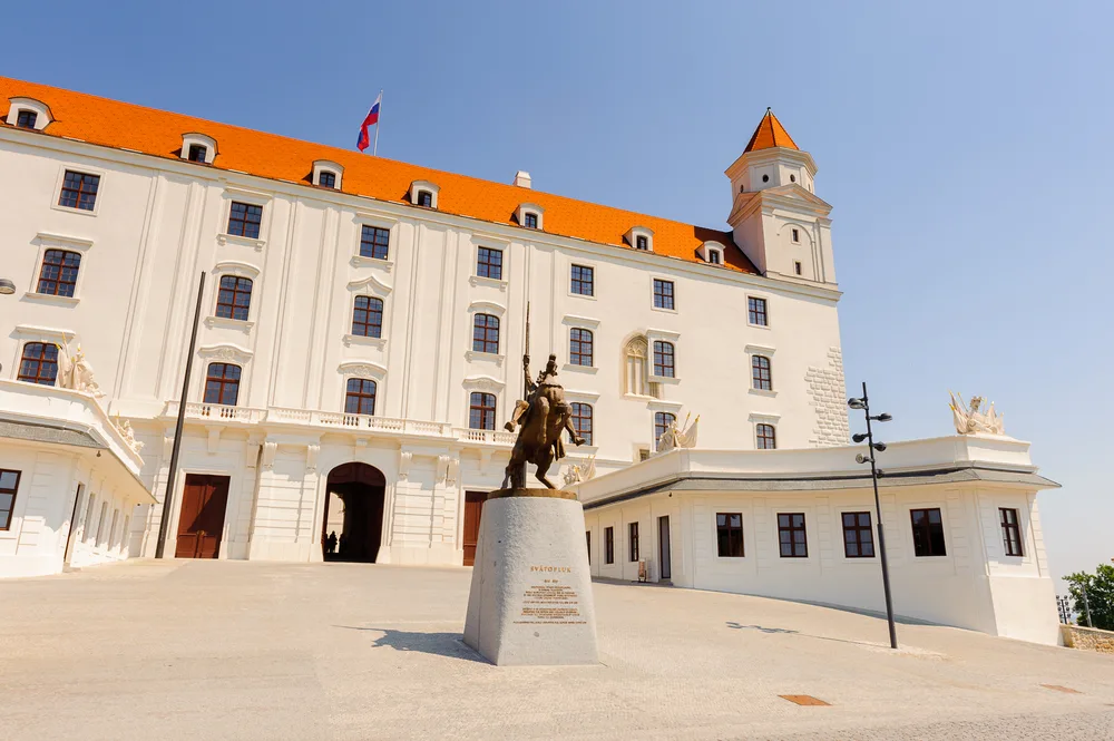 A Terracotta and White Castle with a Statue in Front