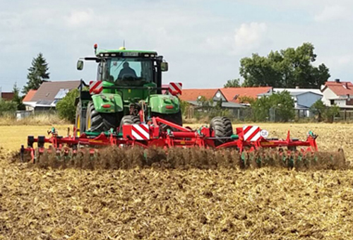 Cultivateur à dents Kverneland Turbo au travail dans un champ vue de derrière