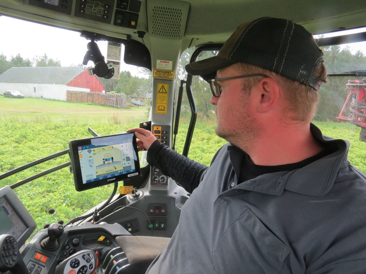 Farmer operating the Kverneland iXtrack T6 sprayer via ISOBUS terminal inside tractor cab.