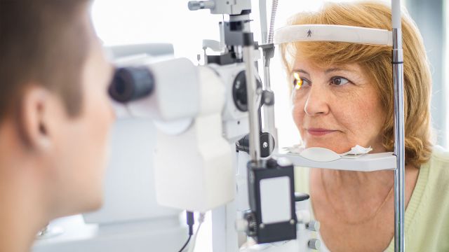 Photo of healthcare professional using equipment to examine patient's eyes.