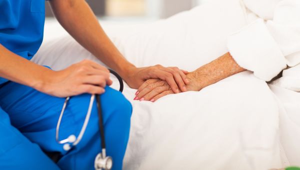 nurse holding patient hand in bed