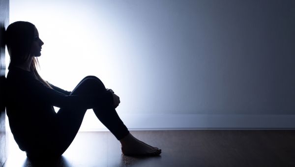 woman leaning against wall in the dark, moody, depression