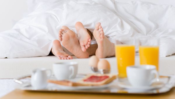 Luxury hotel honeymoon breakfast - couple in white bed together