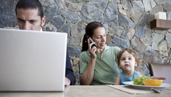 woman on phone talking while husband works on laptop