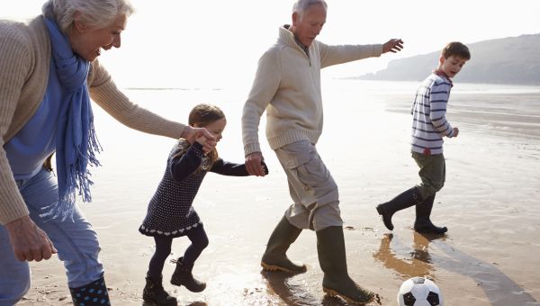 grandparents playing soccer on the beach with grandsons