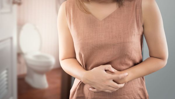 stomach ache, woman holding her stomach, toilet in background