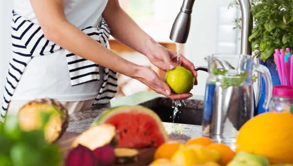 woman washing fruit in sink water