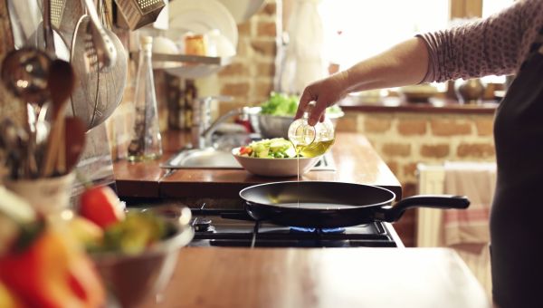 Person pouring vegetable oil into cooking pan