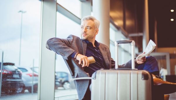 Senior man waiting at airport with suitcase