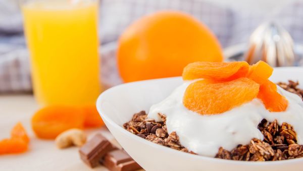 Granola with dried apricots and yogurt in a white bowl
