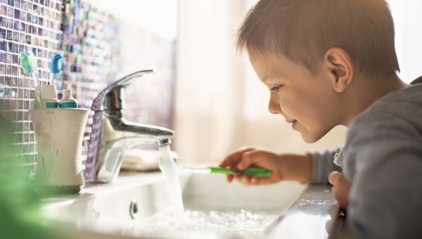 boy brushing teeth over sink