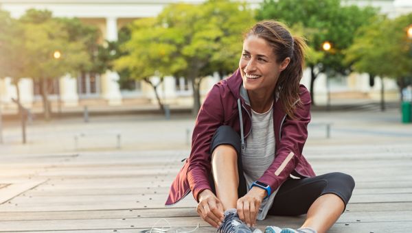 Woman sitting lacing up running shoes