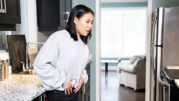 young woman pelvic pain in kitchen